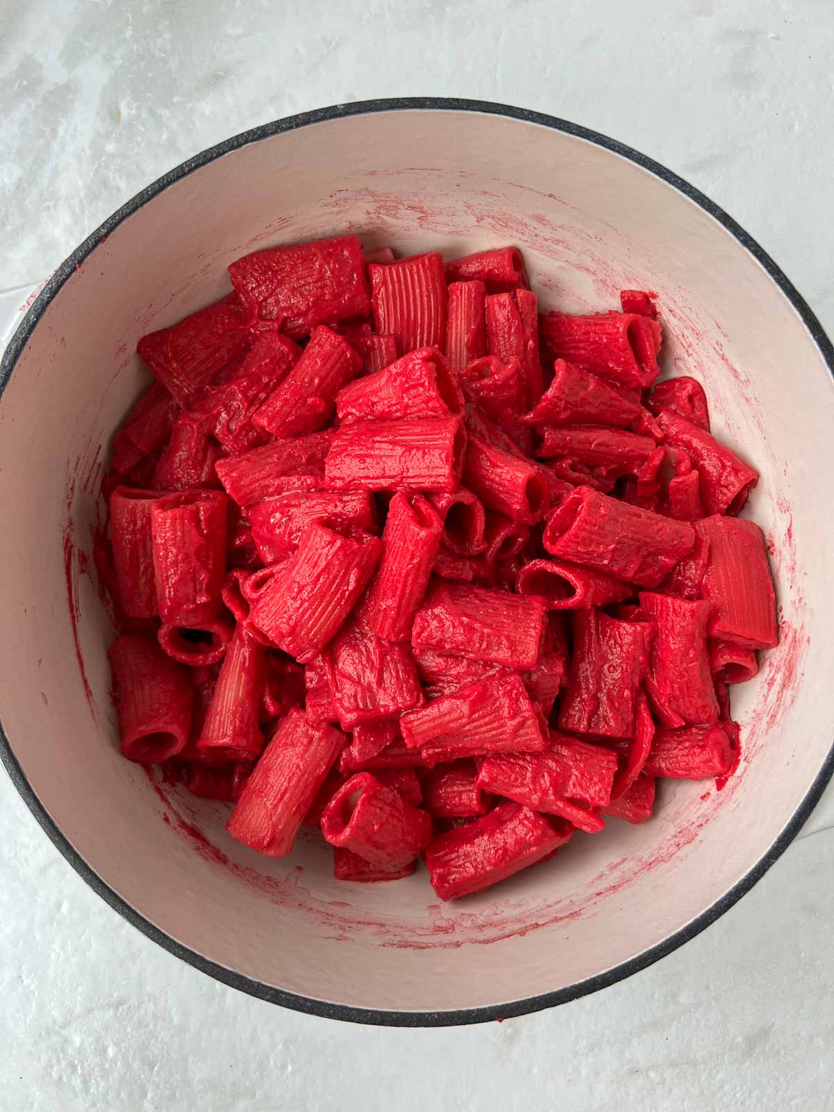 Cooked pasta with beet sauce in a pot.