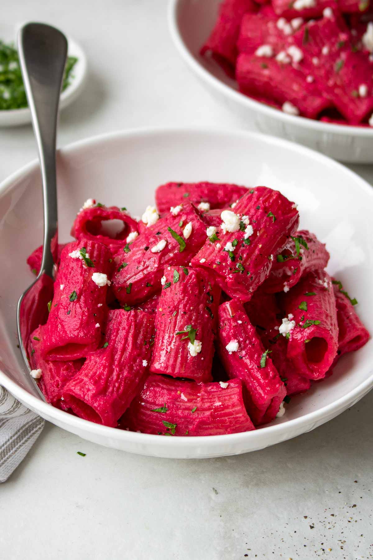 Two bowls of pasta with beet pasta sauce in a bowl.