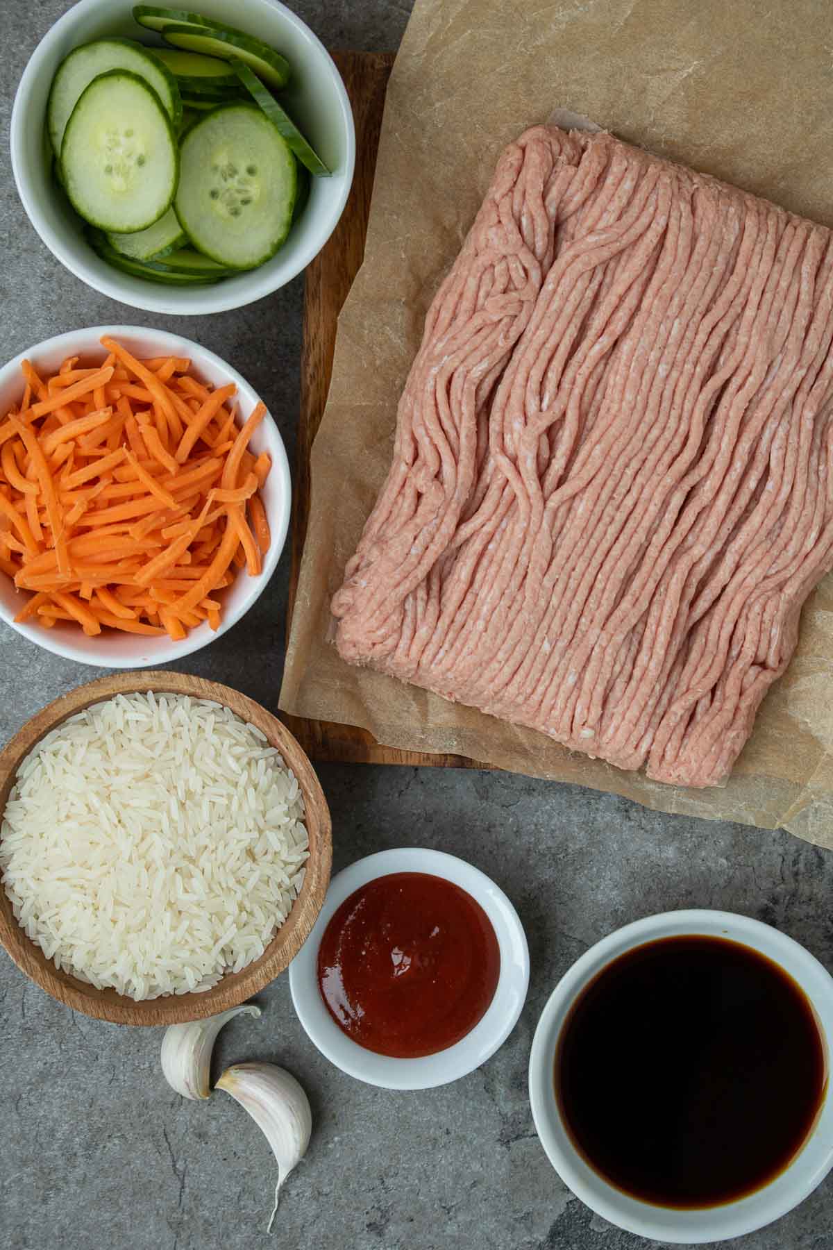 Ingredients for Korean ground turkey rice bowl recipe; ground turkey, soy sauce, gochujang, garlic, rice, shredded carrots, and sliced cucumber.