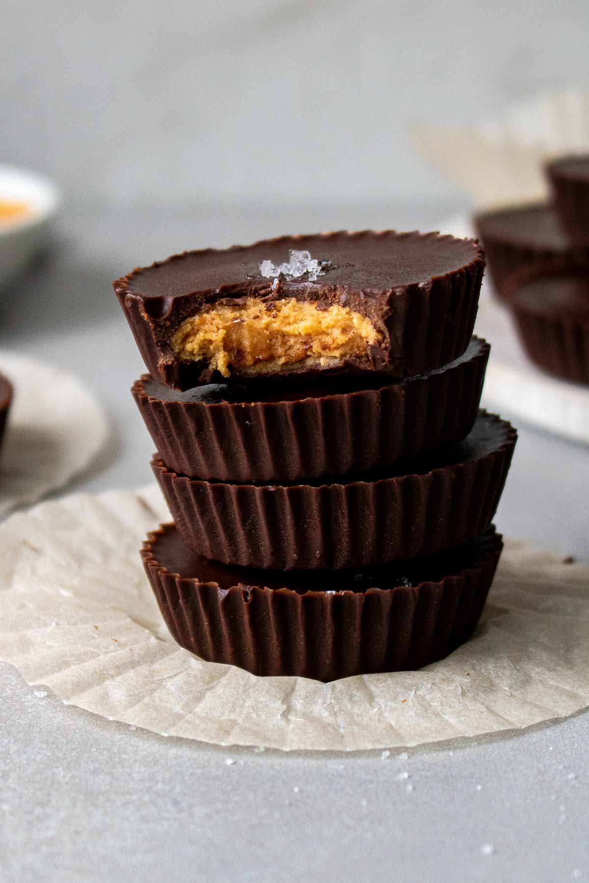 A stack of four homemade dark chocolate peanut butter cups with a bite taken from the top one