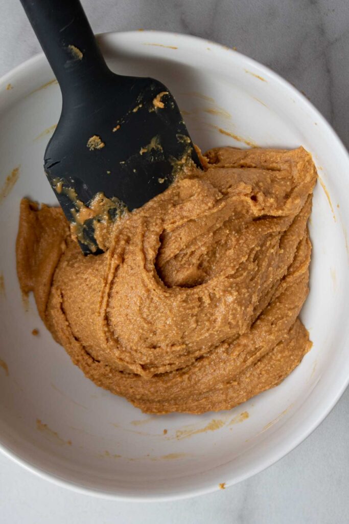 A white bowl containing peanut butter mixture with a spatula