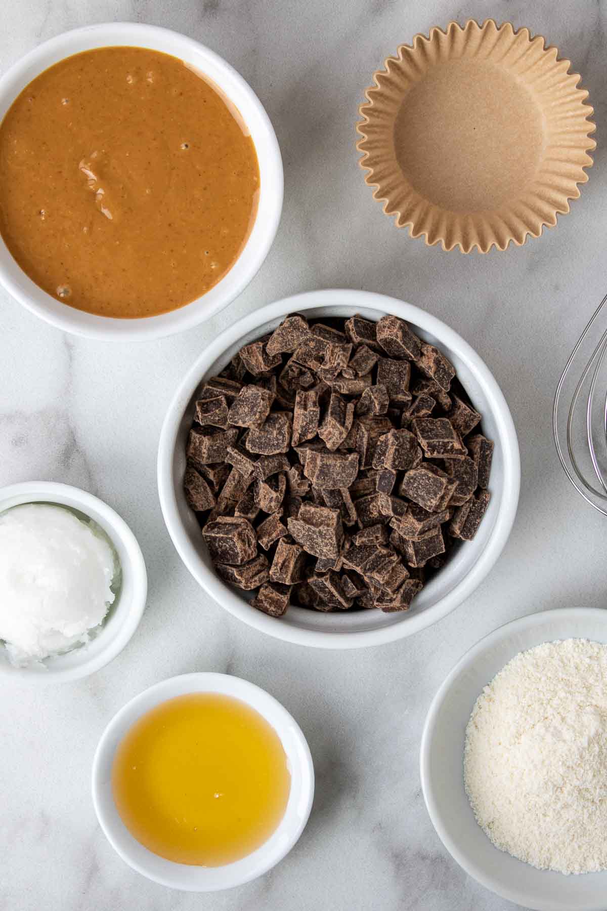 Ingredients for dark chocolate peanut butter cups; natural peanut butter, muffin liners, dark chocolate chips, coconut oil, honey, and coconut flour