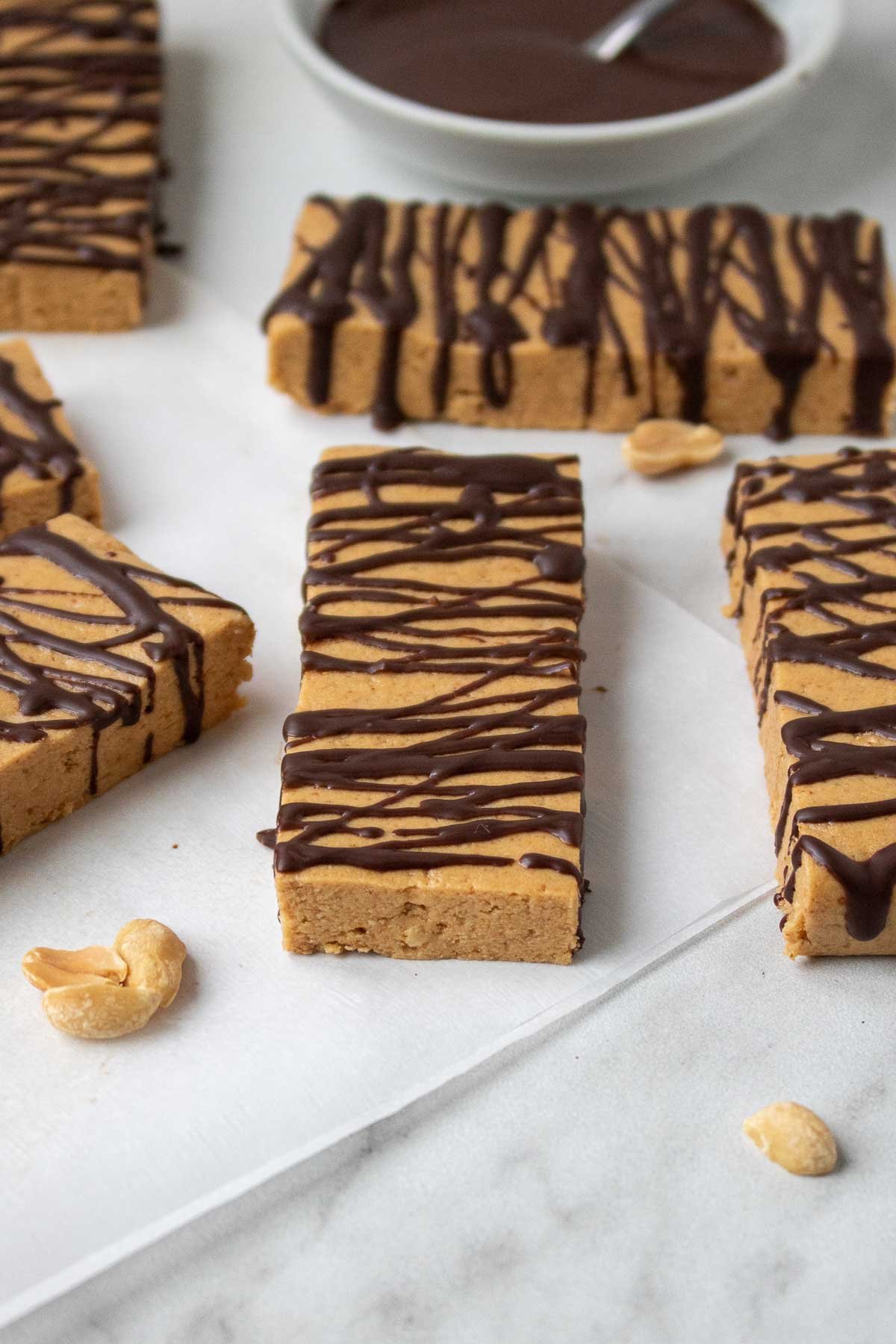 Homemade peanut butter protein bars with a dark chocolate drizzle on parchment paper.