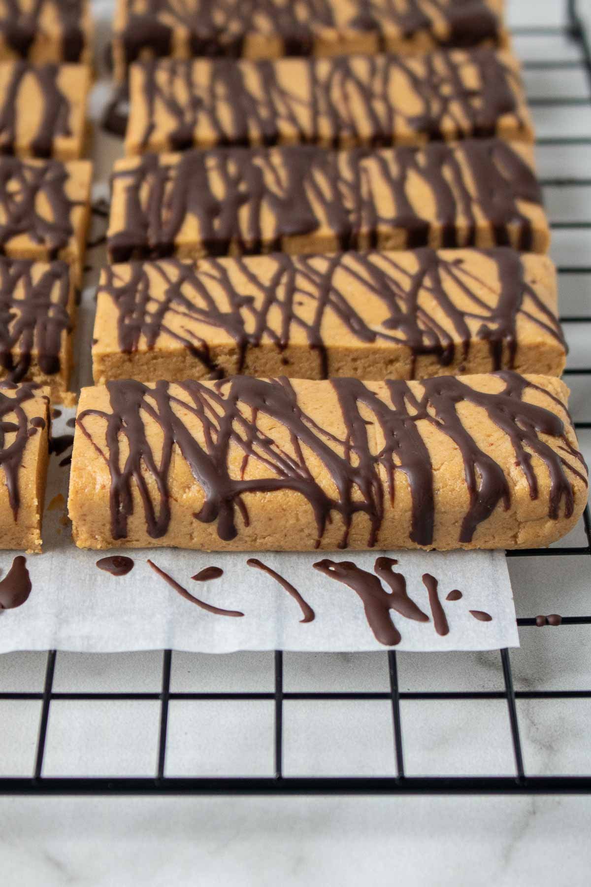 Protein bars on a baking rack with chocolate drizzled on top.