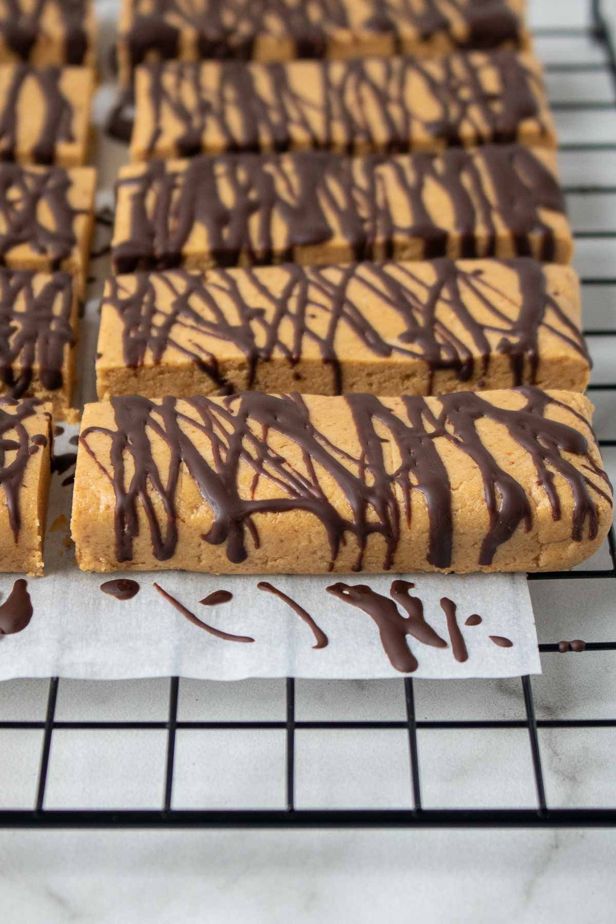 Barres protéinées sur une grille de cuisson avec du chocolat drizzled on top.