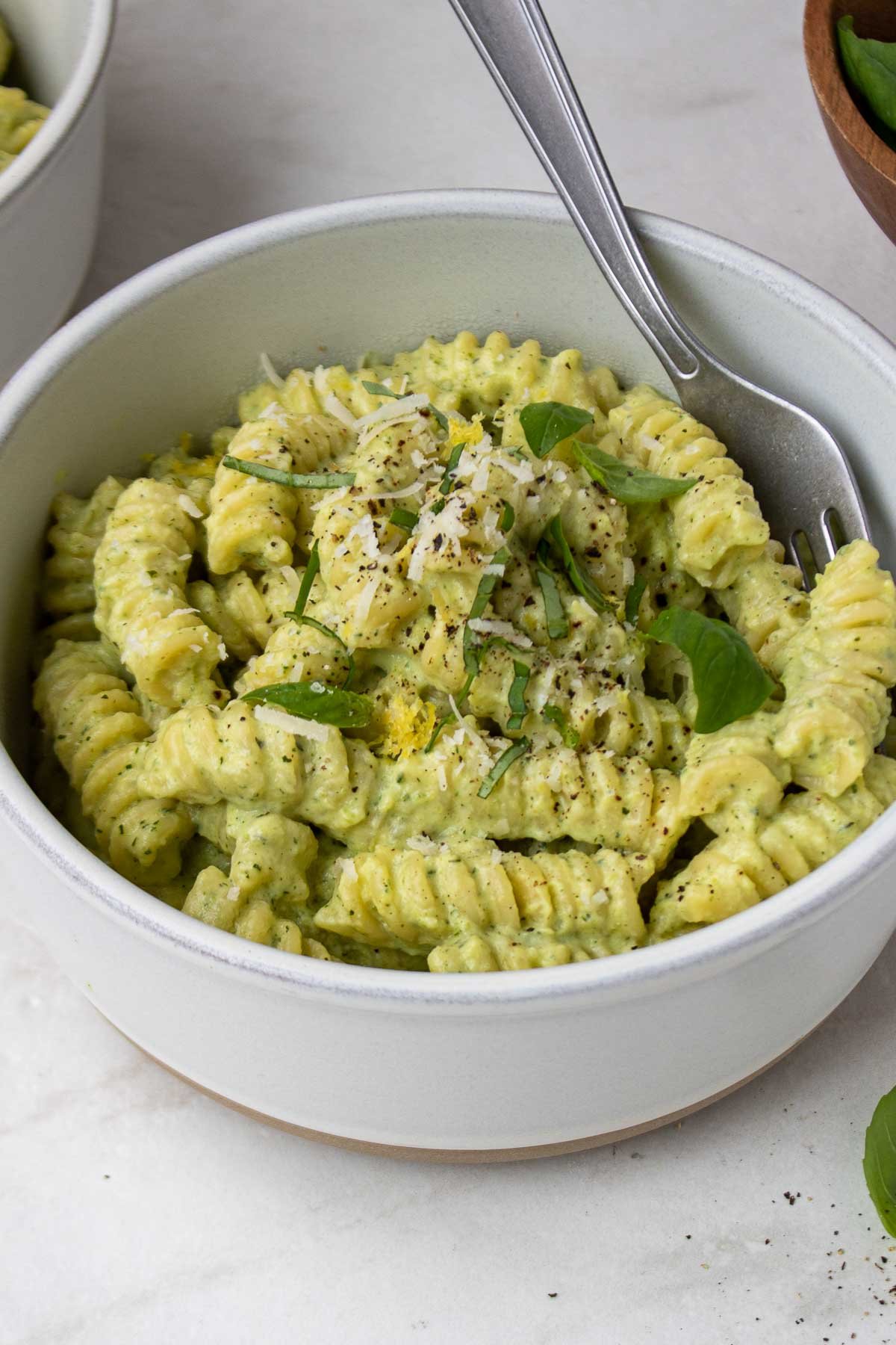 Close up of pasta with creamy zucchini pasta sauce in a white bowl with a fork.