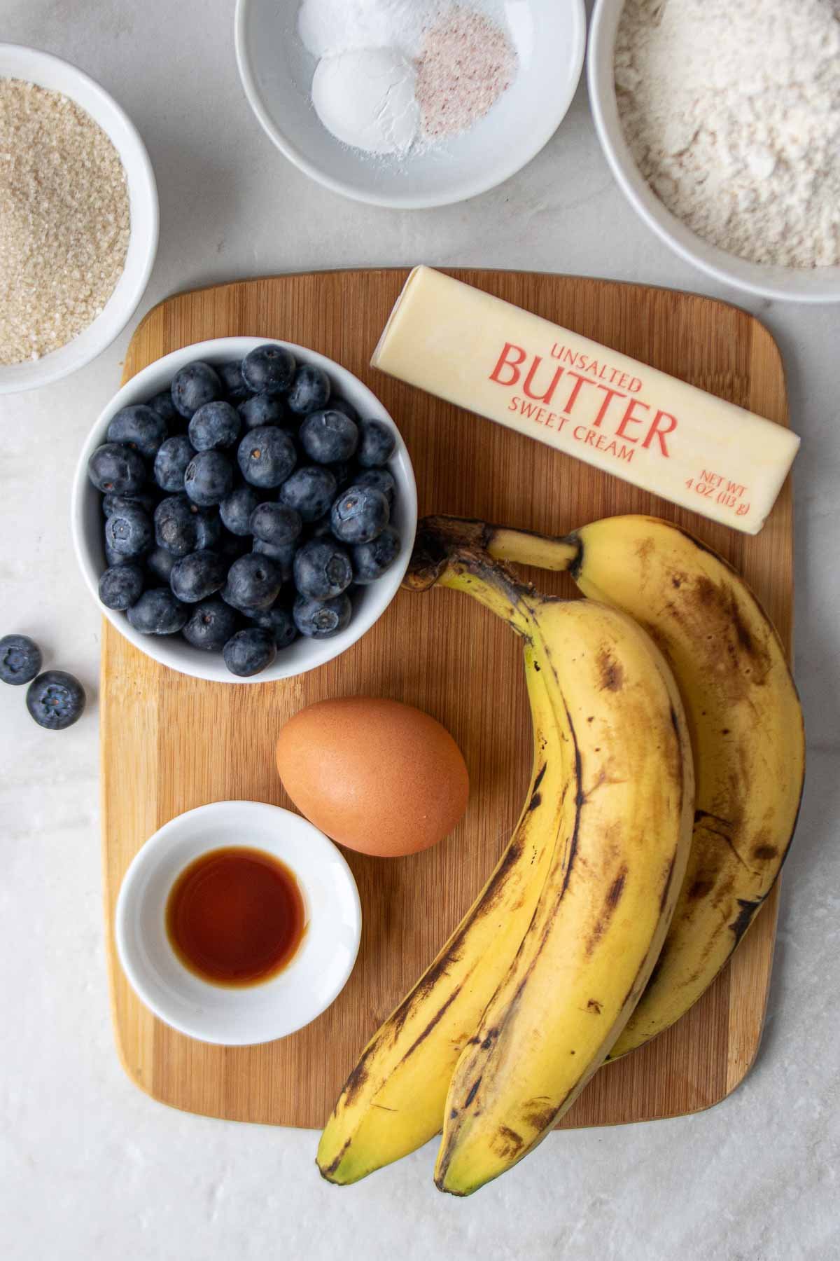 Ingrédients pour les muffins à la banane et aux myrtilles : farine, bicarbonate de soude, levure chimique, sel, sucre, oeuf, extrait de vanille, beurre, bananes, myrtilles