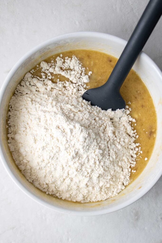 Bowl with wet ingredients and dry ingredients in a white bowl with a spatula