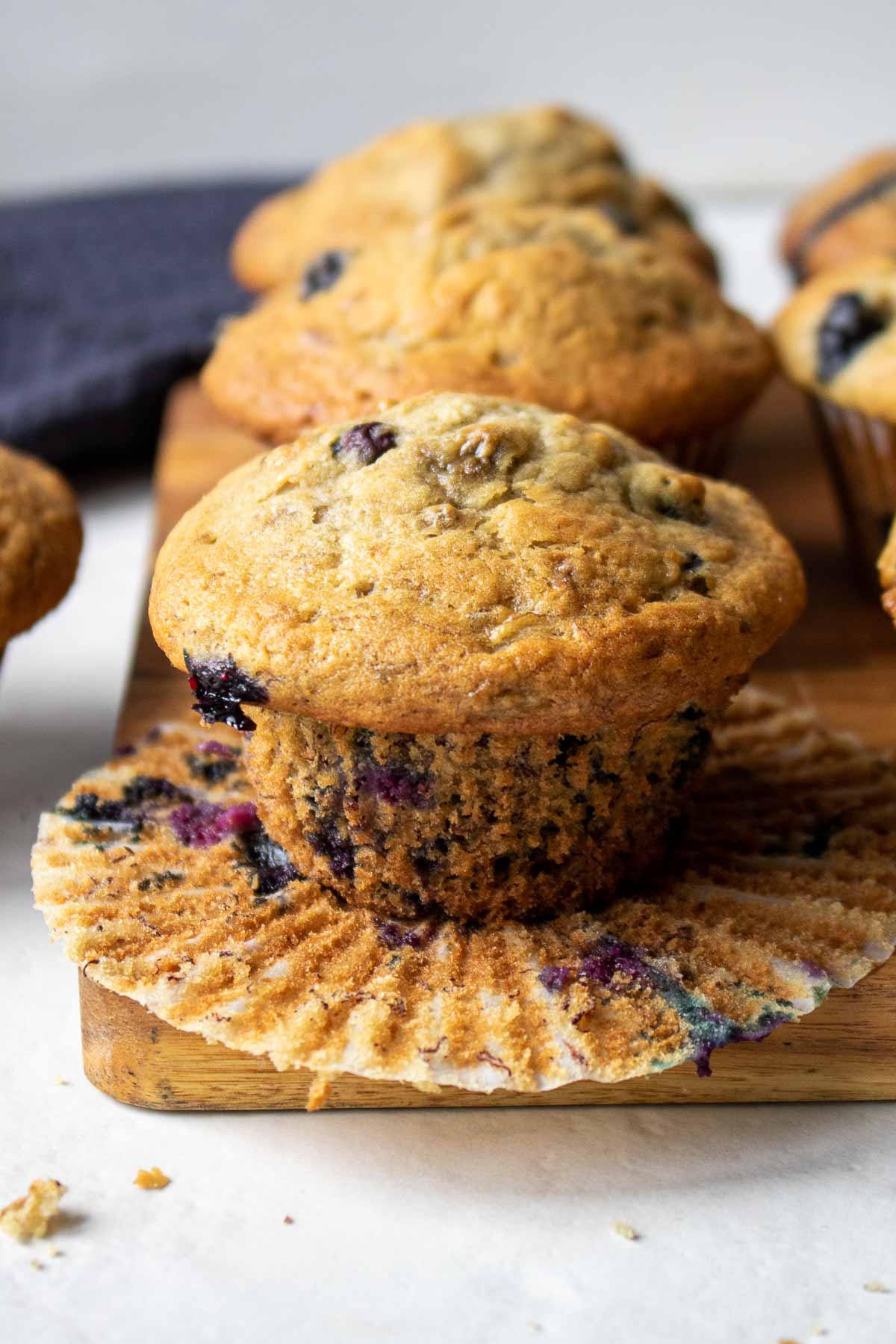 Muffins à la banane et aux myrtilles sur une planche à découper dans une caissette de muffin ouverte prêts à être dégustés