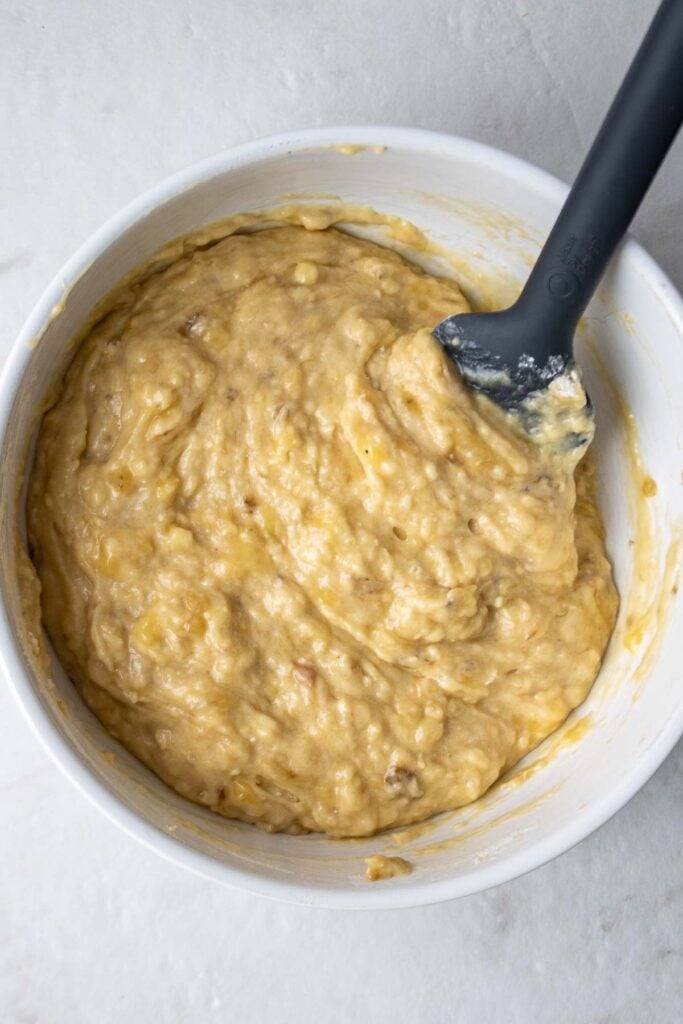 Mixed muffin batter in a white bowl with a spatula