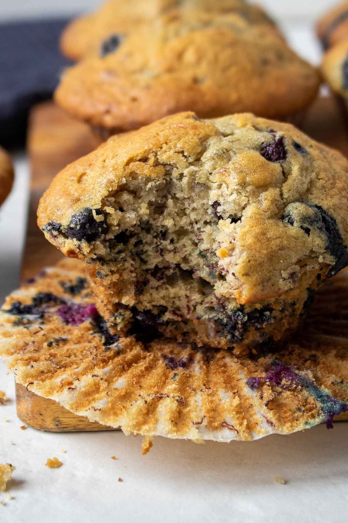 Banana blueberry muffin on a cutting board with a bite eaten
