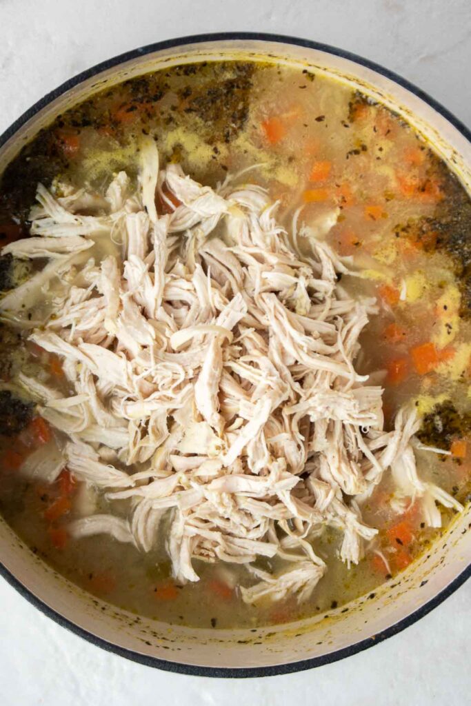 Shredded chicken in a pot with orzo soup