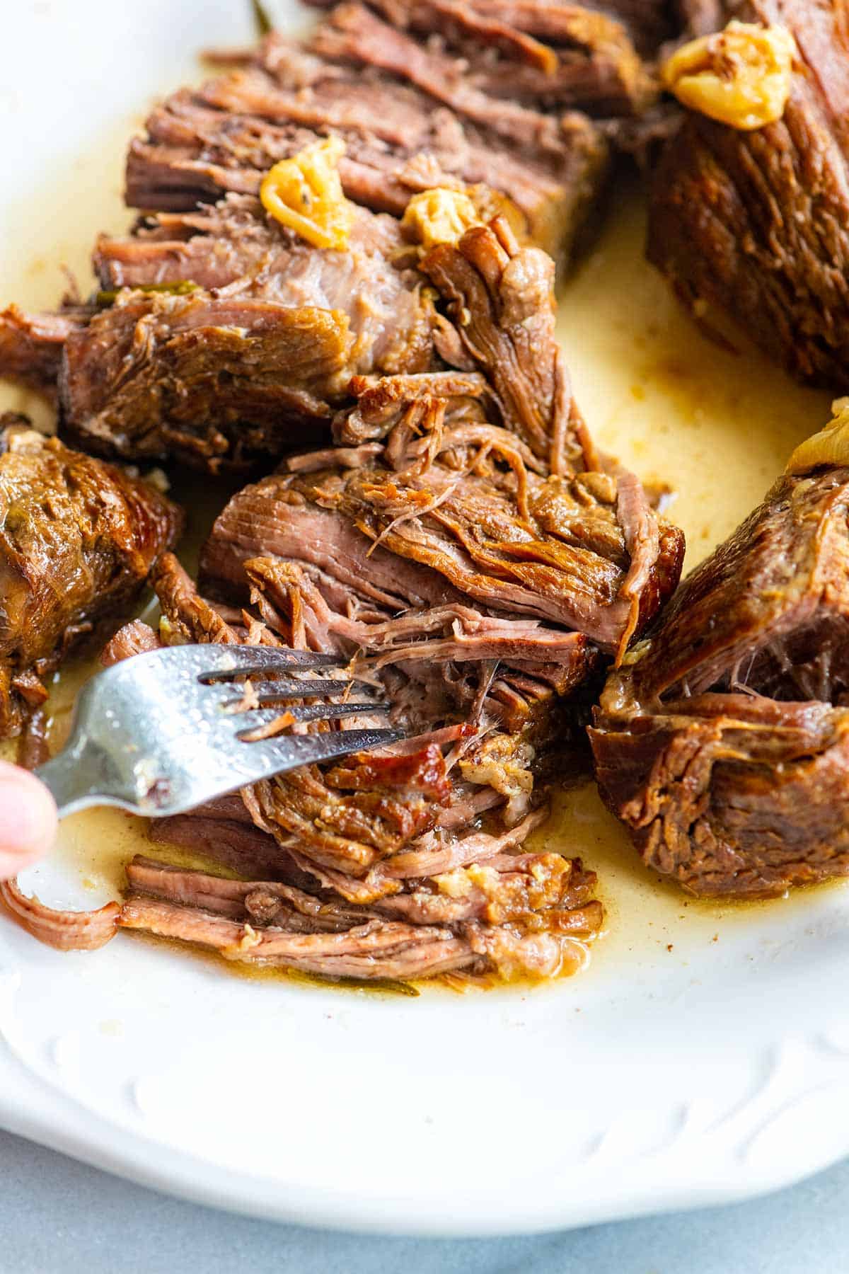 Tender pot roast being pulled apart with a fork.