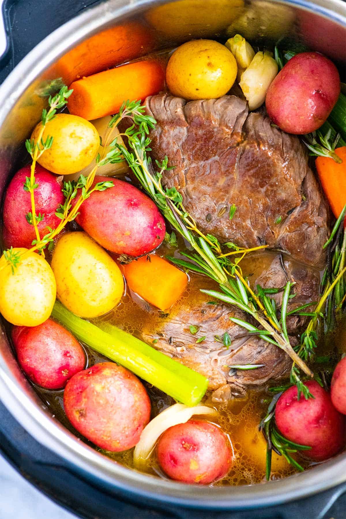 Instant Pot Pot Roast with potatoes, carrots, and herbs.
