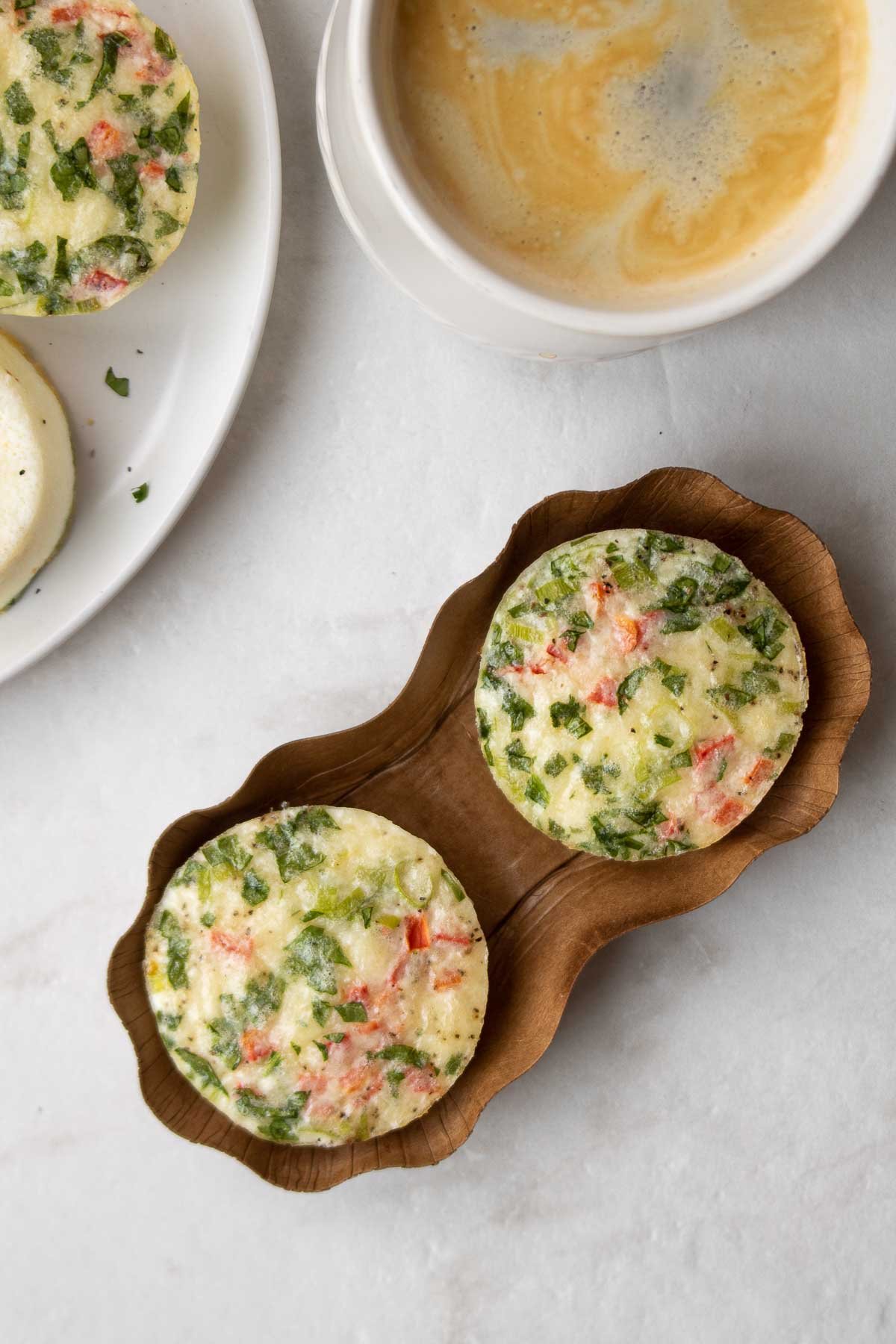 Copycat Starbucks egg white bites with roasted red pepper and spinach in a brown cardboard container with a cup of coffee.