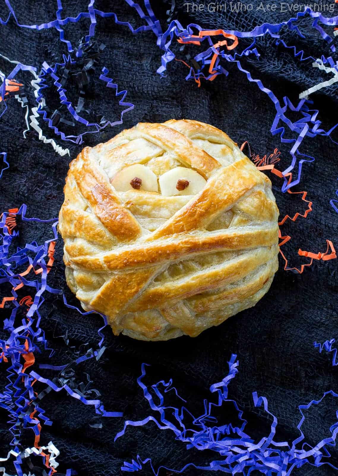 Mummy Wrapped Brie - topped with brown sugar and cinnamon pecans, baked inside puff pastry until nice and gooey. The best appetizer for Halloween! the-girl-who-ate-everything.com