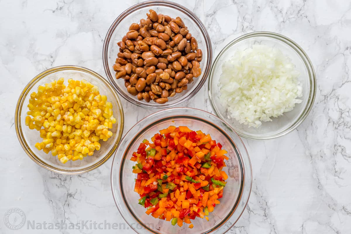 Diced ingredients in glass bowls including beans, corn, onion and peppers