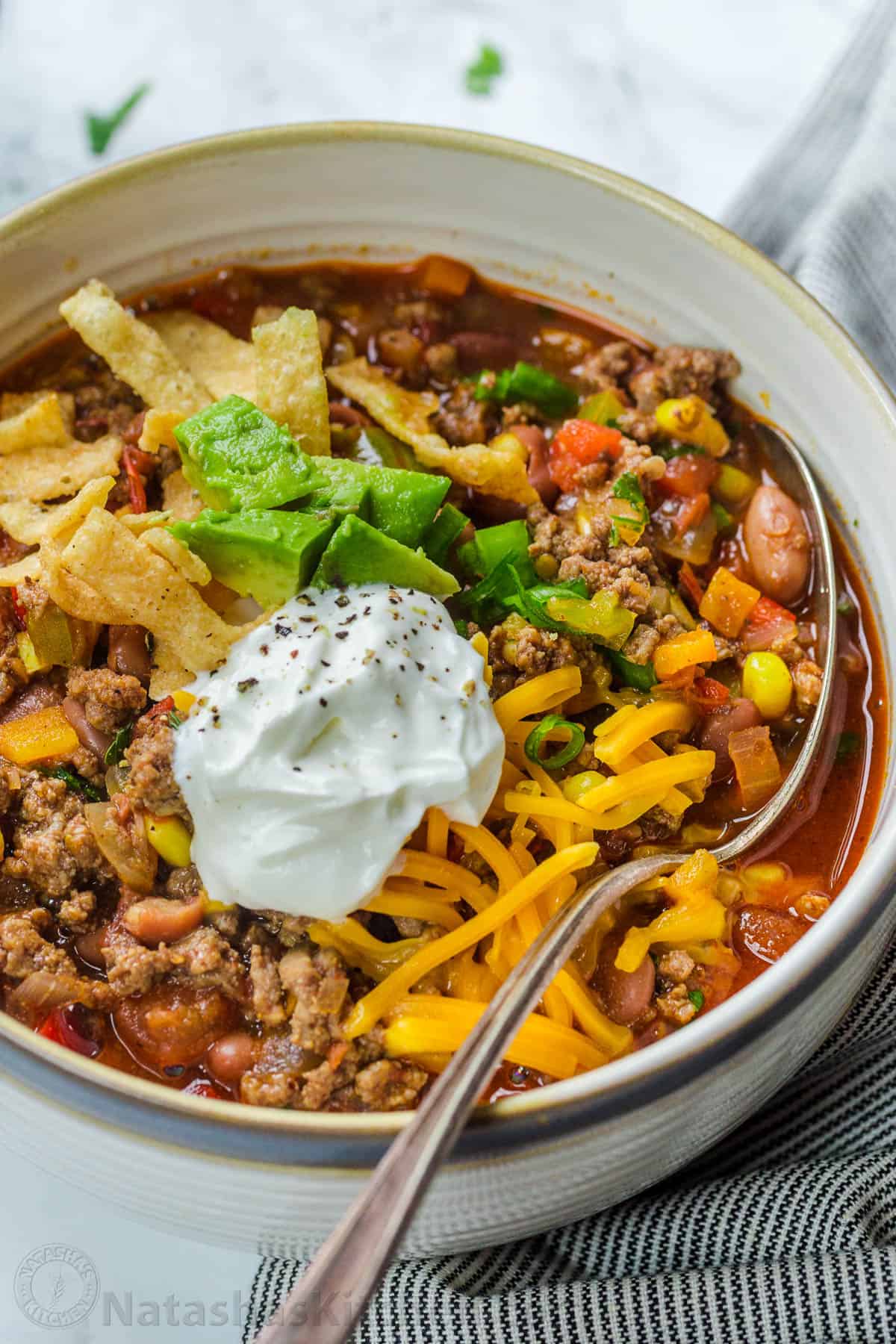 Hearty taco soup in a bowl topped with avocado and cheese.