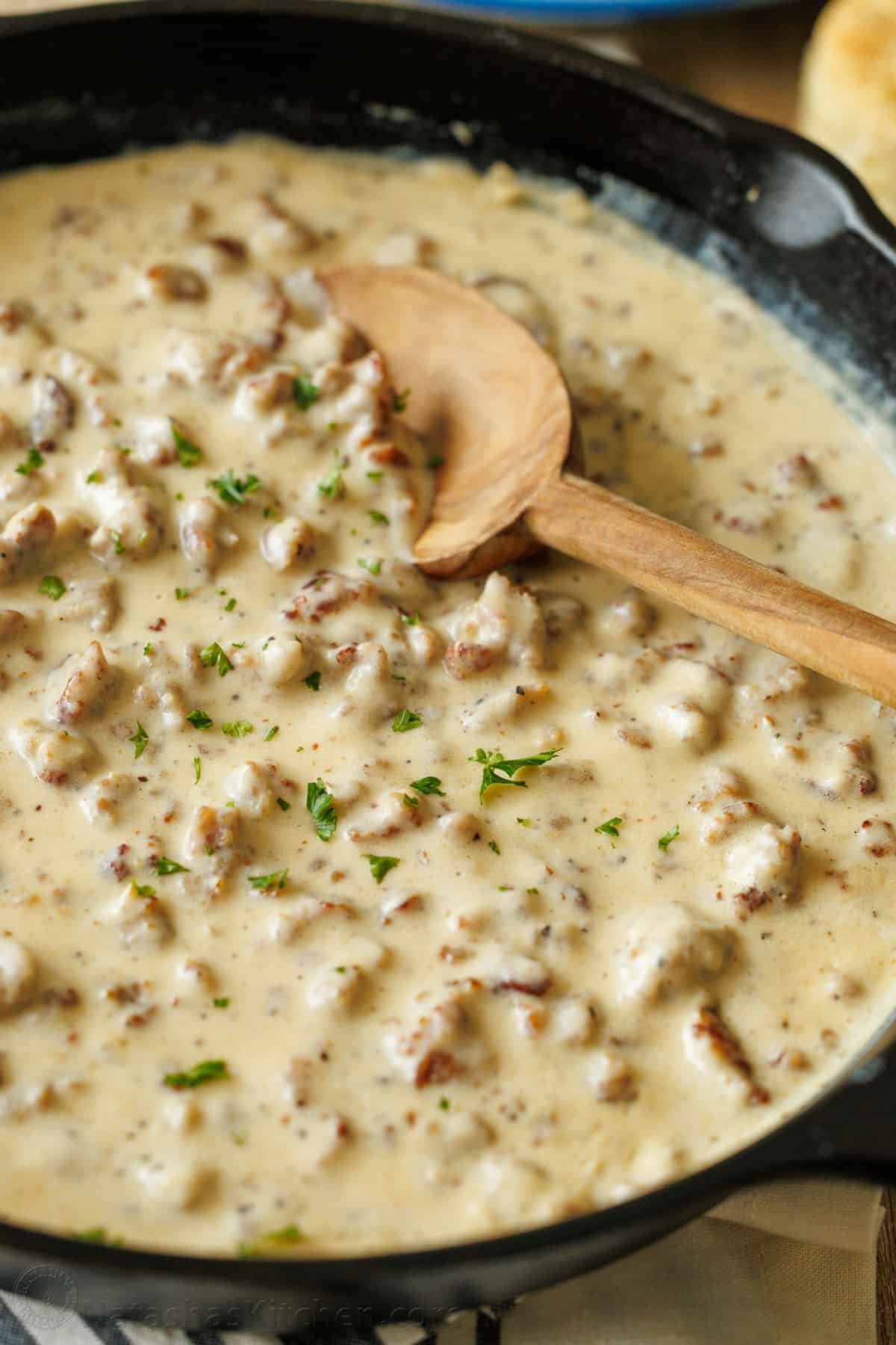 Southern white sauce with pork crumbles in a pan with a wooden spoon