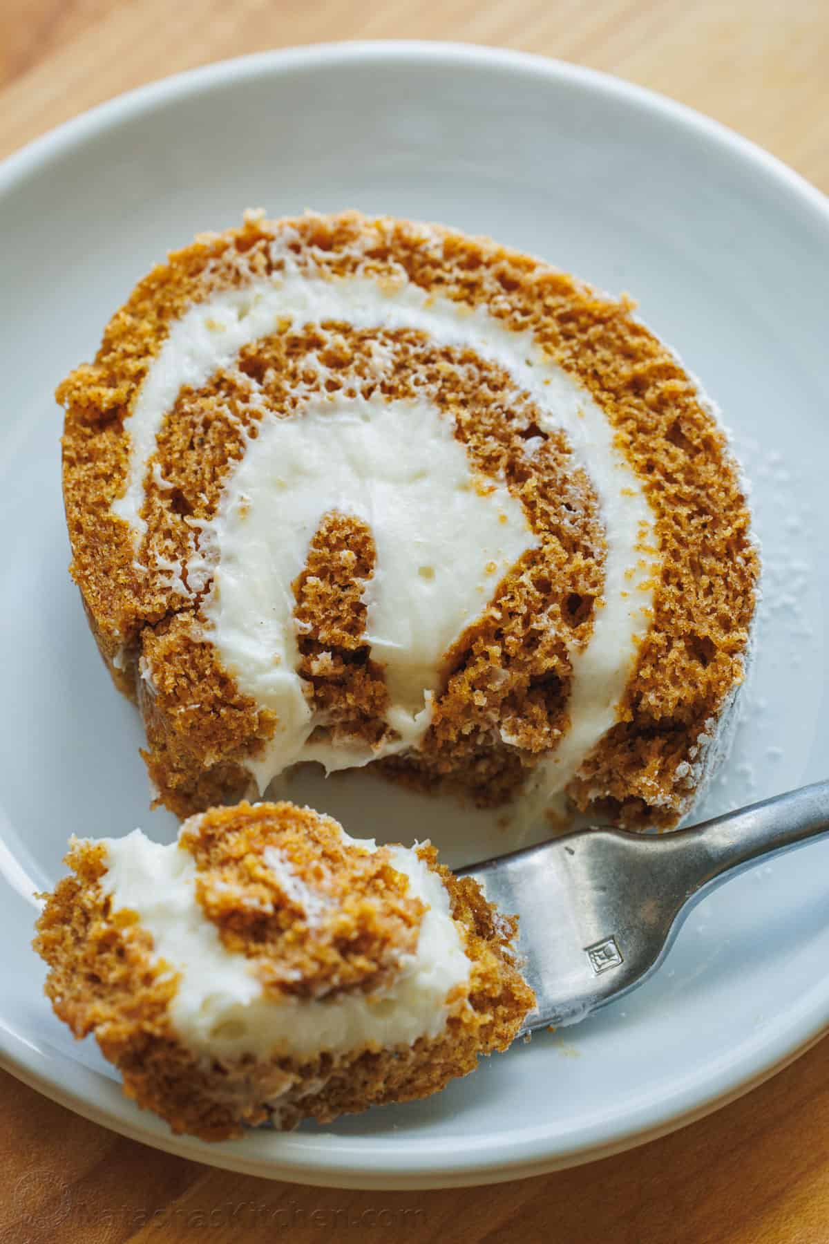 A slice of pumpkin roll with cream cheese filling with a bite taken out