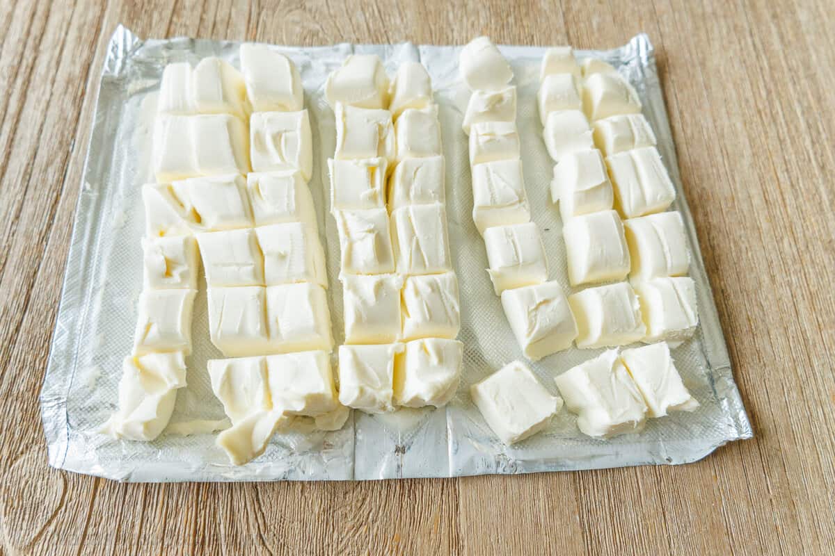 Philadelphia cream cheese blocks cut into cubes on a pan