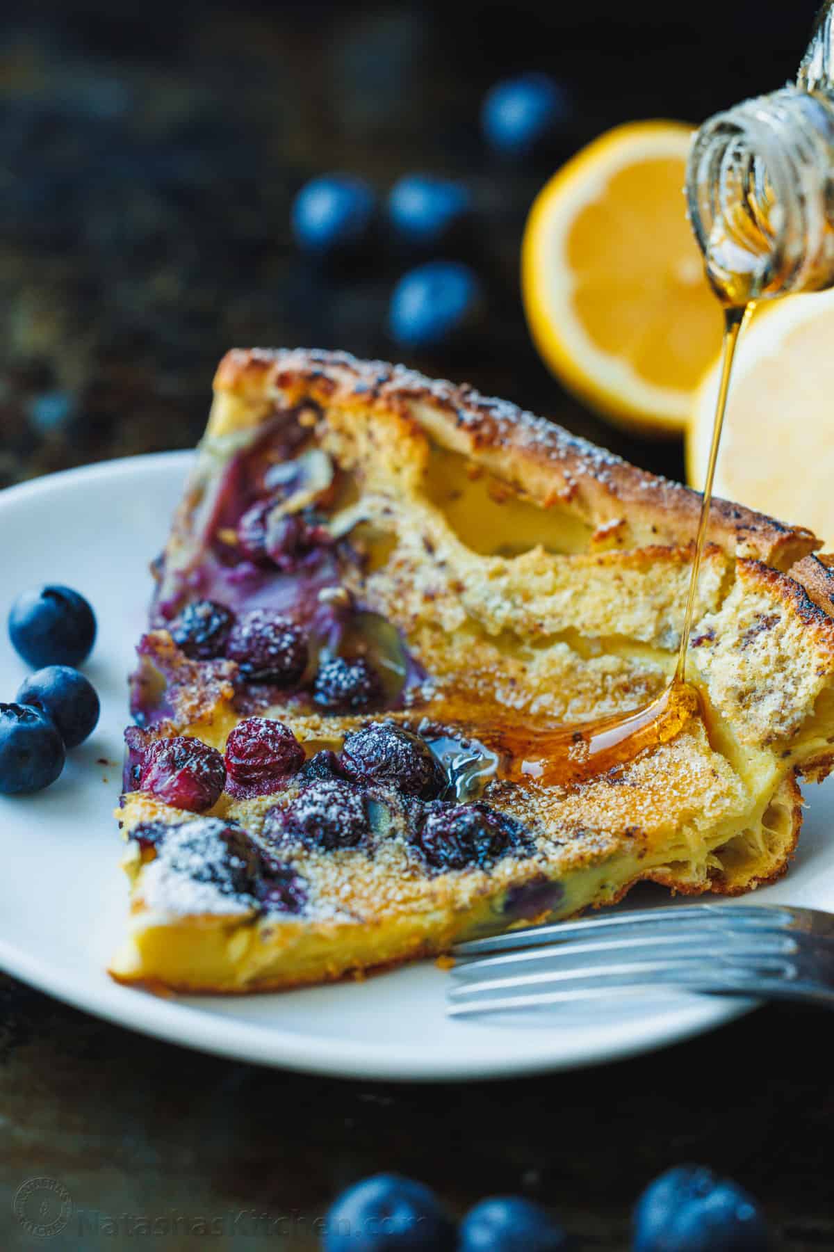 blueberry lemon dutch baby pancake sliced on plate with maple syrup