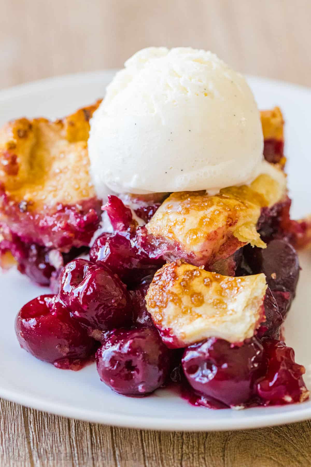 Homemade Cherry Pie Slice on a plate topped with vanilla ice cream
