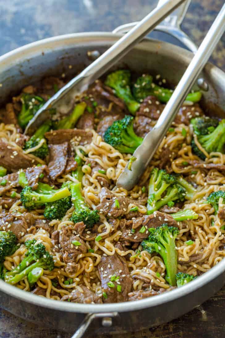 Cooked ramen stir fry in skillet with tongs