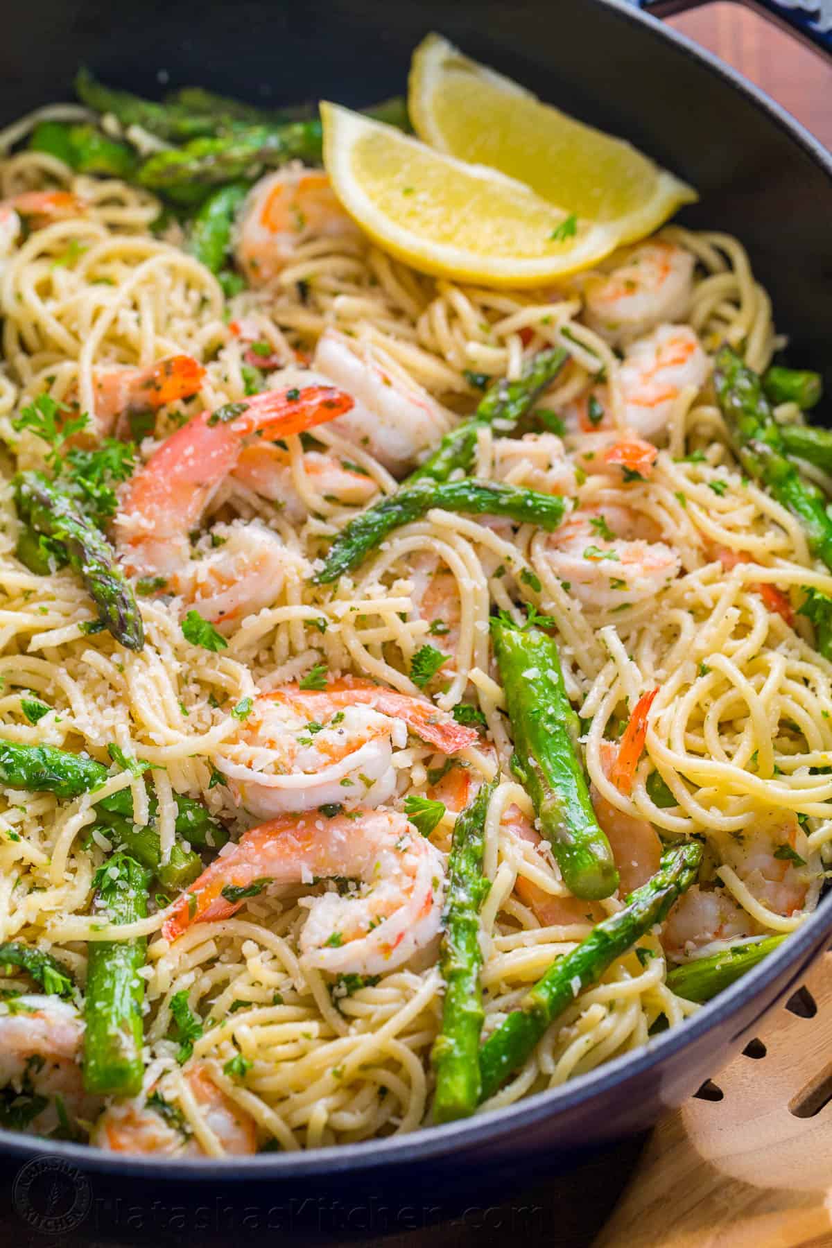 Shrimp scampi pasta garnished with cheese and parsley and lemon wedges