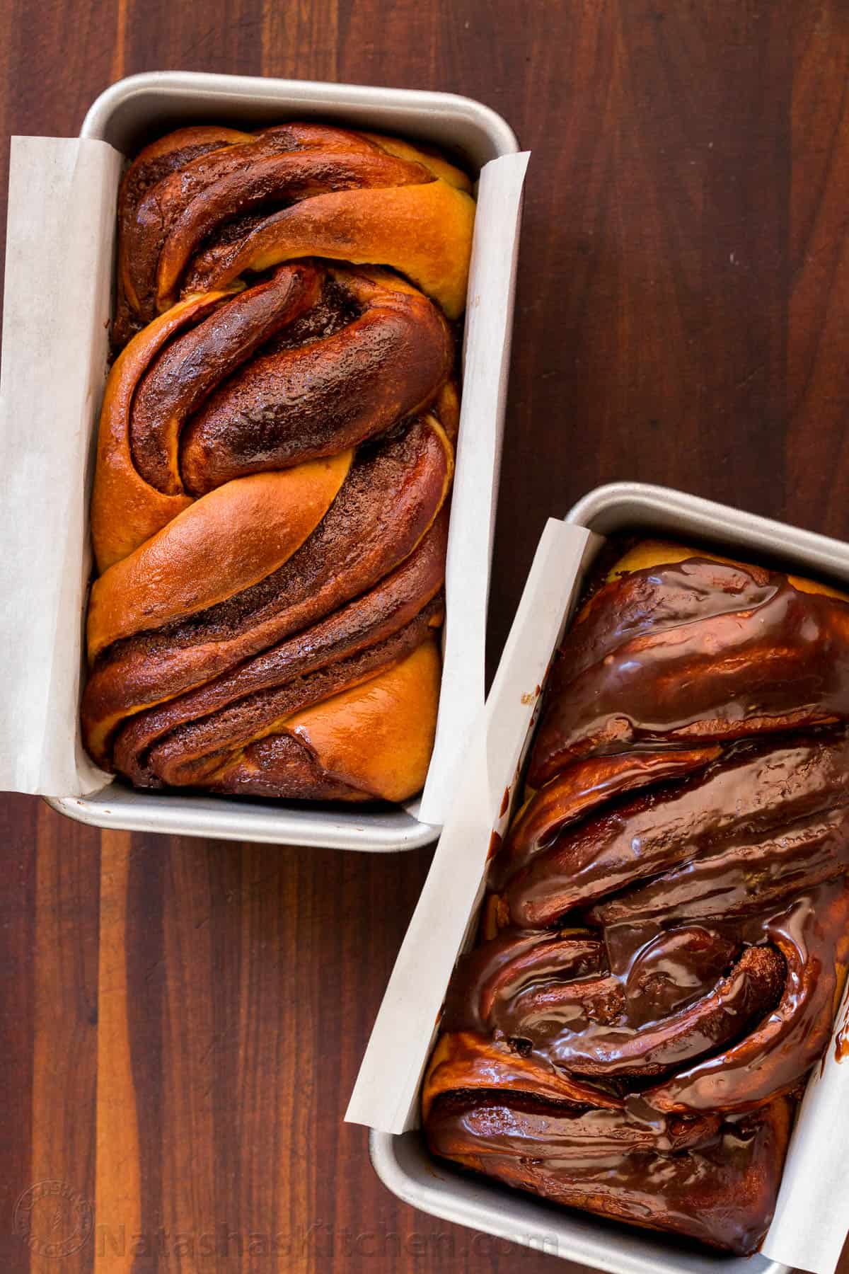 Overhead view of two chocolate babka loaves in two lined loaf pans.