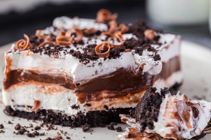 A slice of chocolate lasagna cake on a white plate topped with chocolate shavings.
