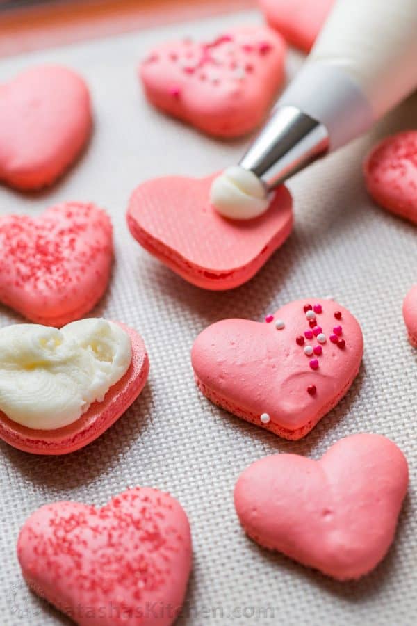 Heart Macarons are easier than you think! Heart-shaped macarons with tangy-sweet lemon buttercream. Includes video tutorial + free printable heart template! | natashaskitchen.com