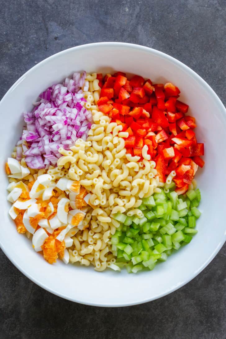 Ingredients prepped ahead for salad with pasta, bell pepper, celery, egg, and onion in a bowl