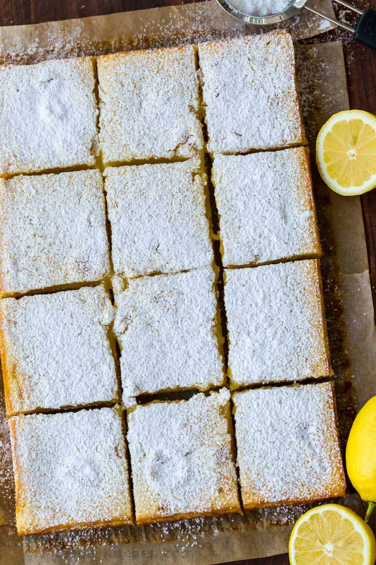 Baked lemon bars cut into squares with lemons