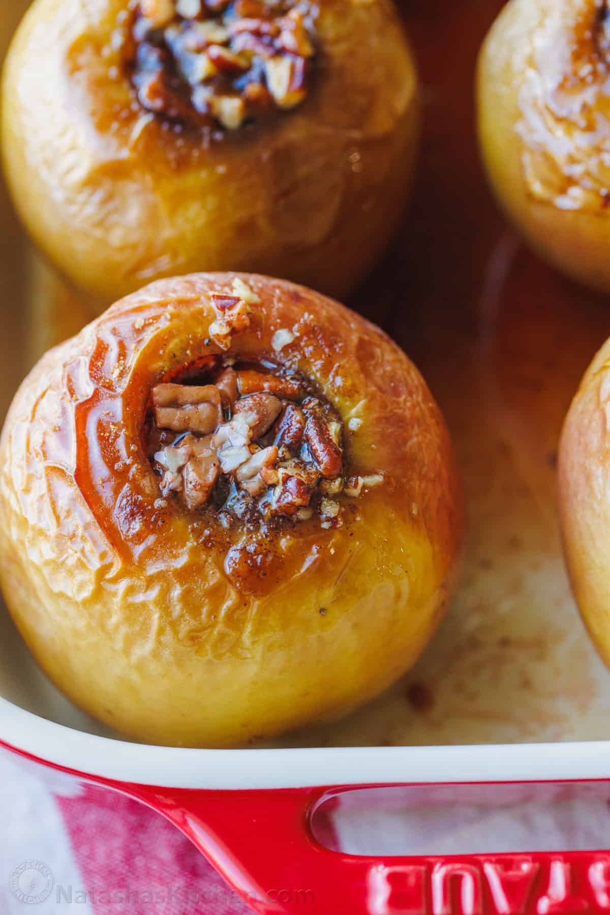 Close up of baked apples filled with cinnamon sugar in a baking dish.