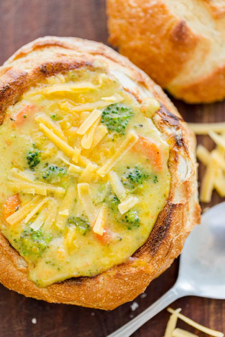 Broccoli Cheese Soup Recipe served in a bread bowl and topped with shredded cheddar cheese