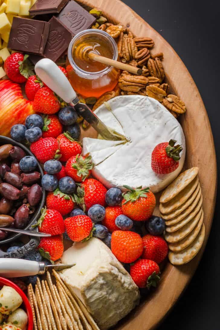 Cheese, fruit, nuts, and condiments arranged on a charcuterie board