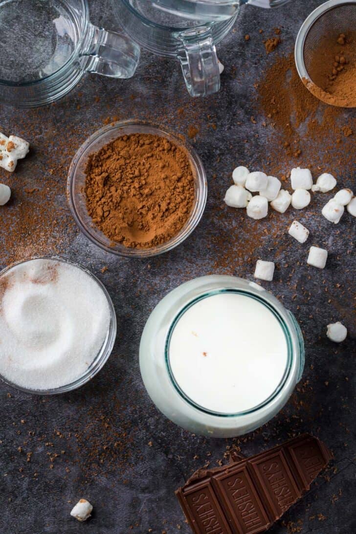 Hot chocolate ingredients on a platter with sugar, milk, and cocoa powder.