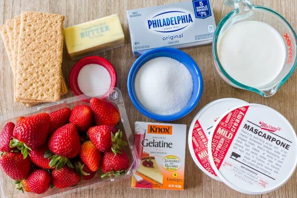 Ingredients for strawberry cheesecake with strawberries, cream cheese, cream, mascarpone, gelatin, graham crackers, and butter