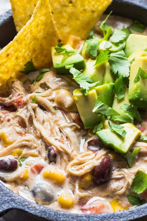 Instant Pot white bean chicken chili up close in a black bowl garnished with avocado, cilantro, and tortilla chips