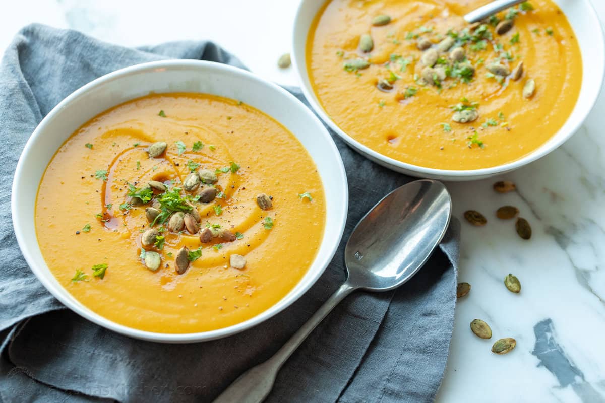 Two bowls of butternut squash soup garnished with pepitas.