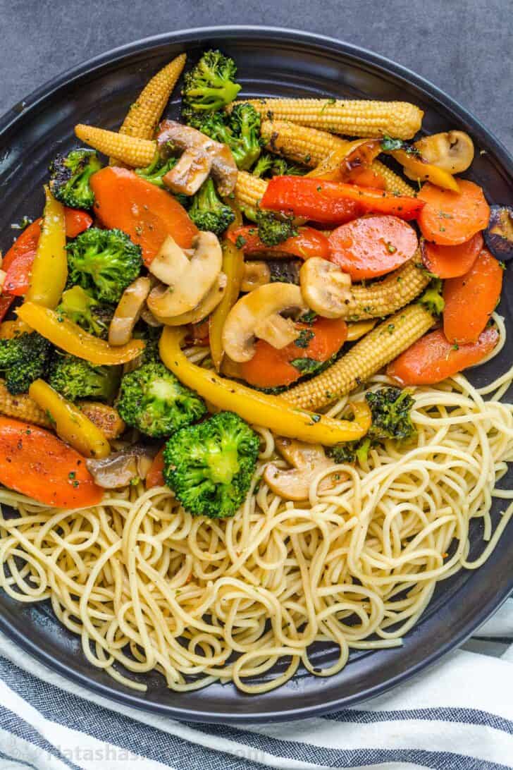 Stir fry vegetables on a plate with a side of noodles.
