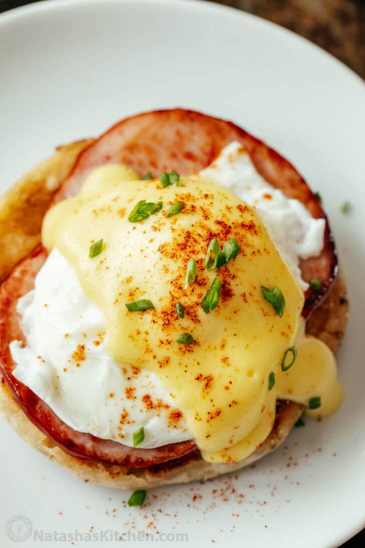 Egg Benedict served on a plate topped with poached egg and hollandaise sauce