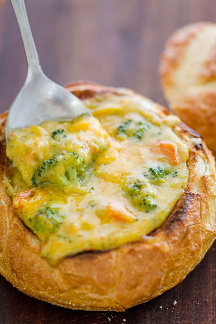 Broccoli cheese soup served in a bread bowl with a spoon in the bread bowl