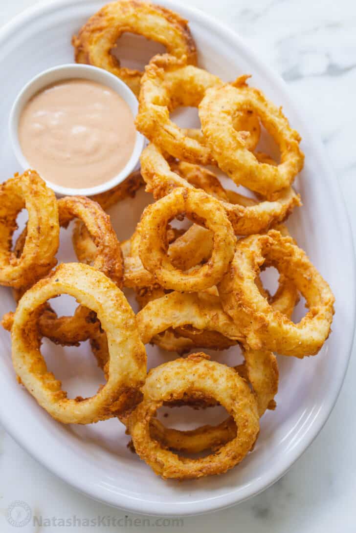 Onion rings on plate with small bowl of dipping sauce