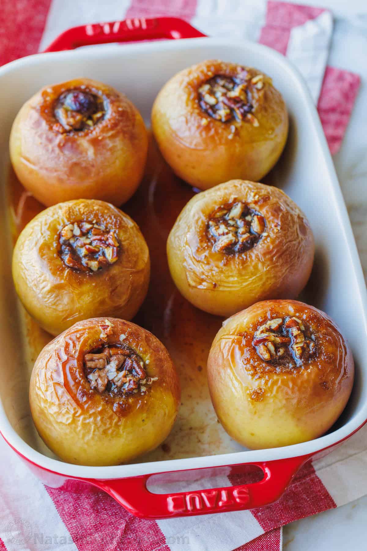 Baked apples filled with cinnamon sugar in a rectangular baking dish.