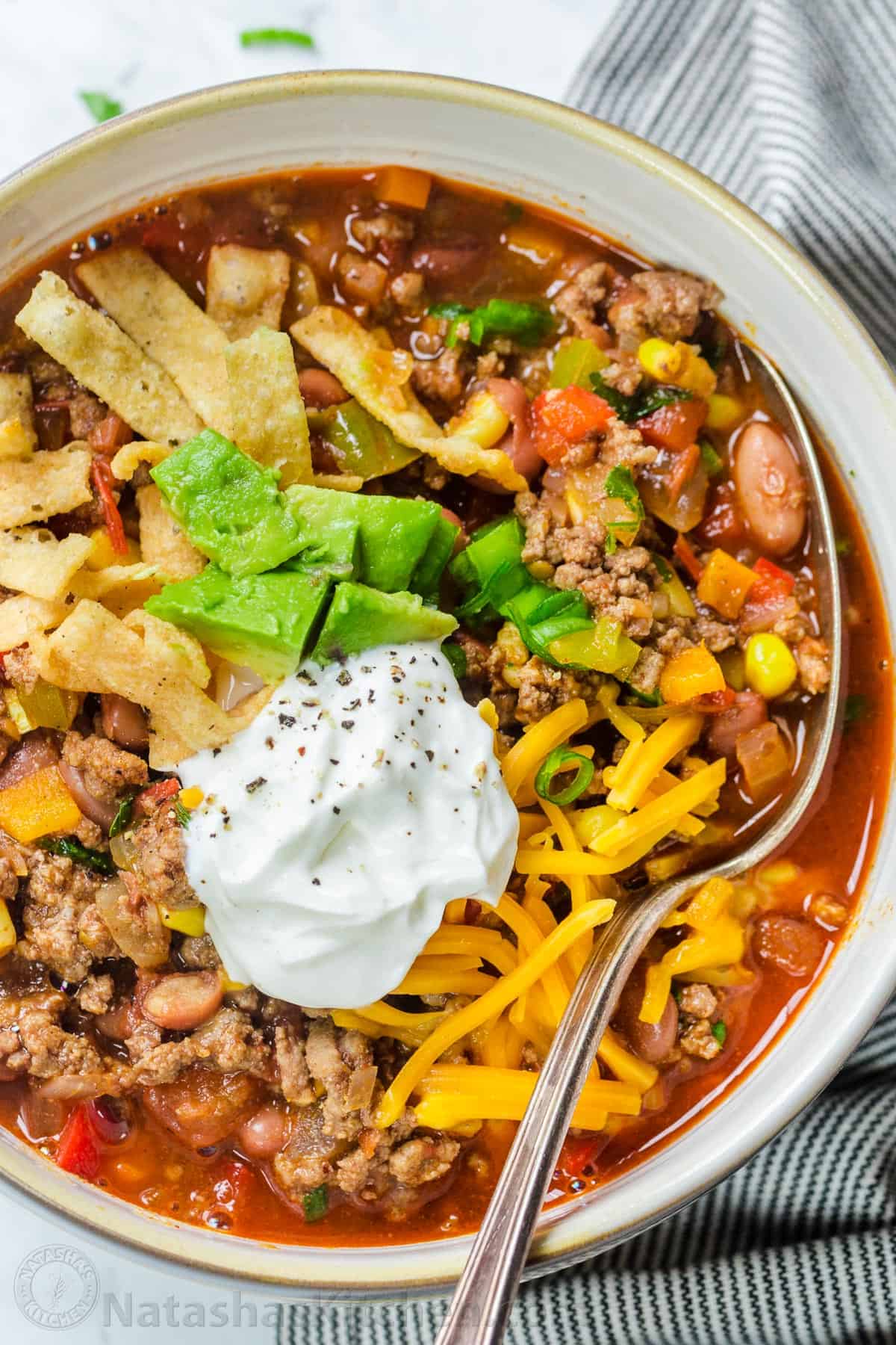 Taco soup in a bowl loaded with tortilla chips, cheese, sour cream and avocado.