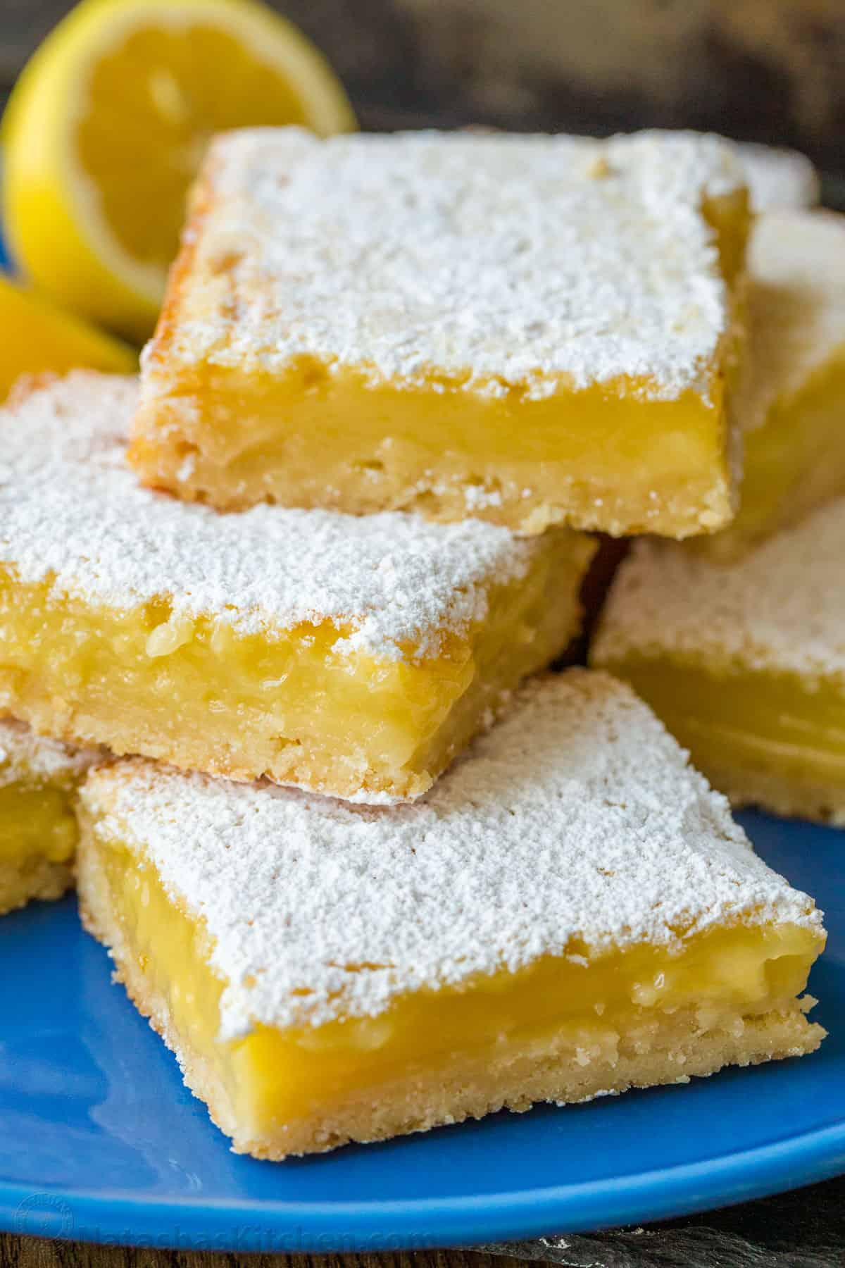 Lemon bars stacked on a blue plate