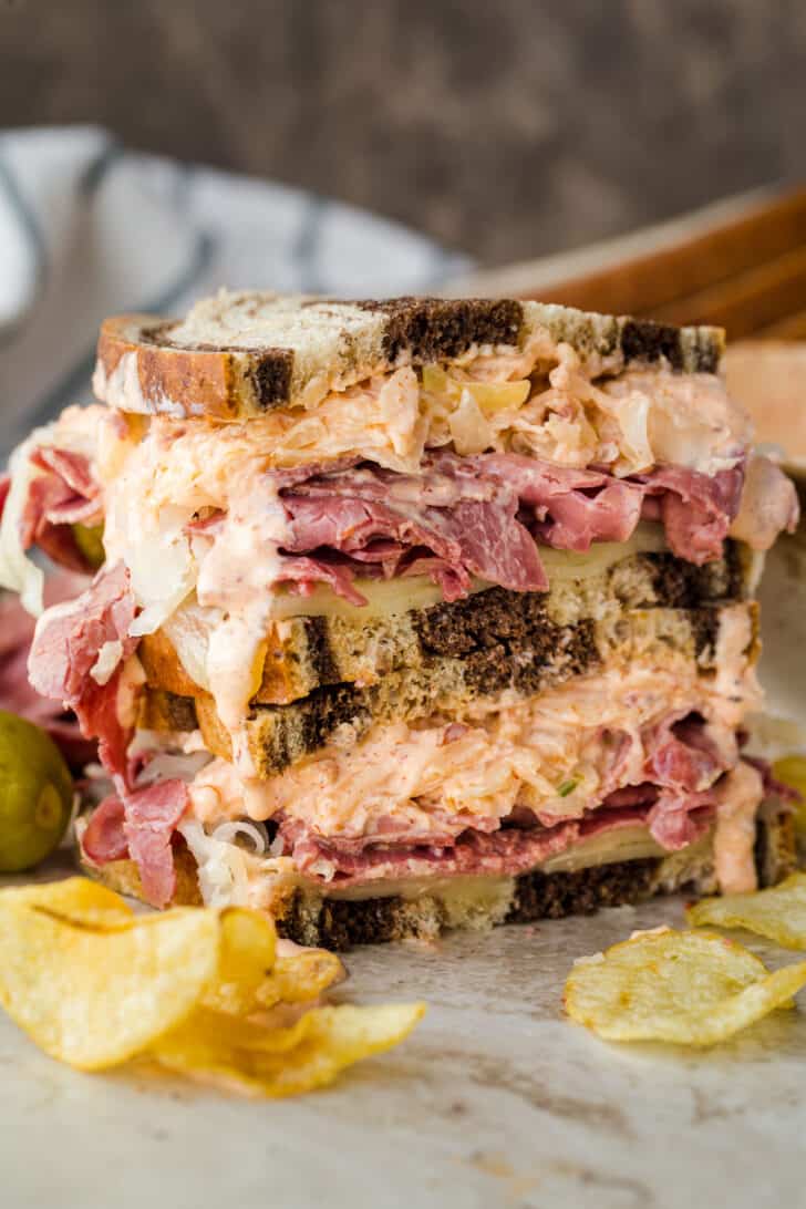 Homemade Reuben Sandwich stacked with a side of chips.