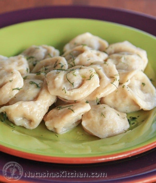 A green plate with Russian pelmeni garnished with dill
